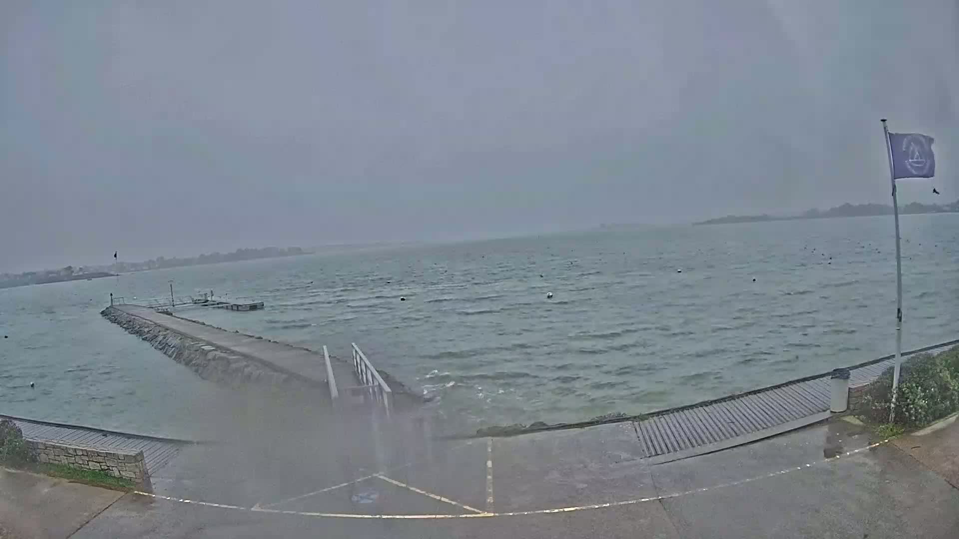 A stone pier extends into a choppy, gray sea under an overcast sky.