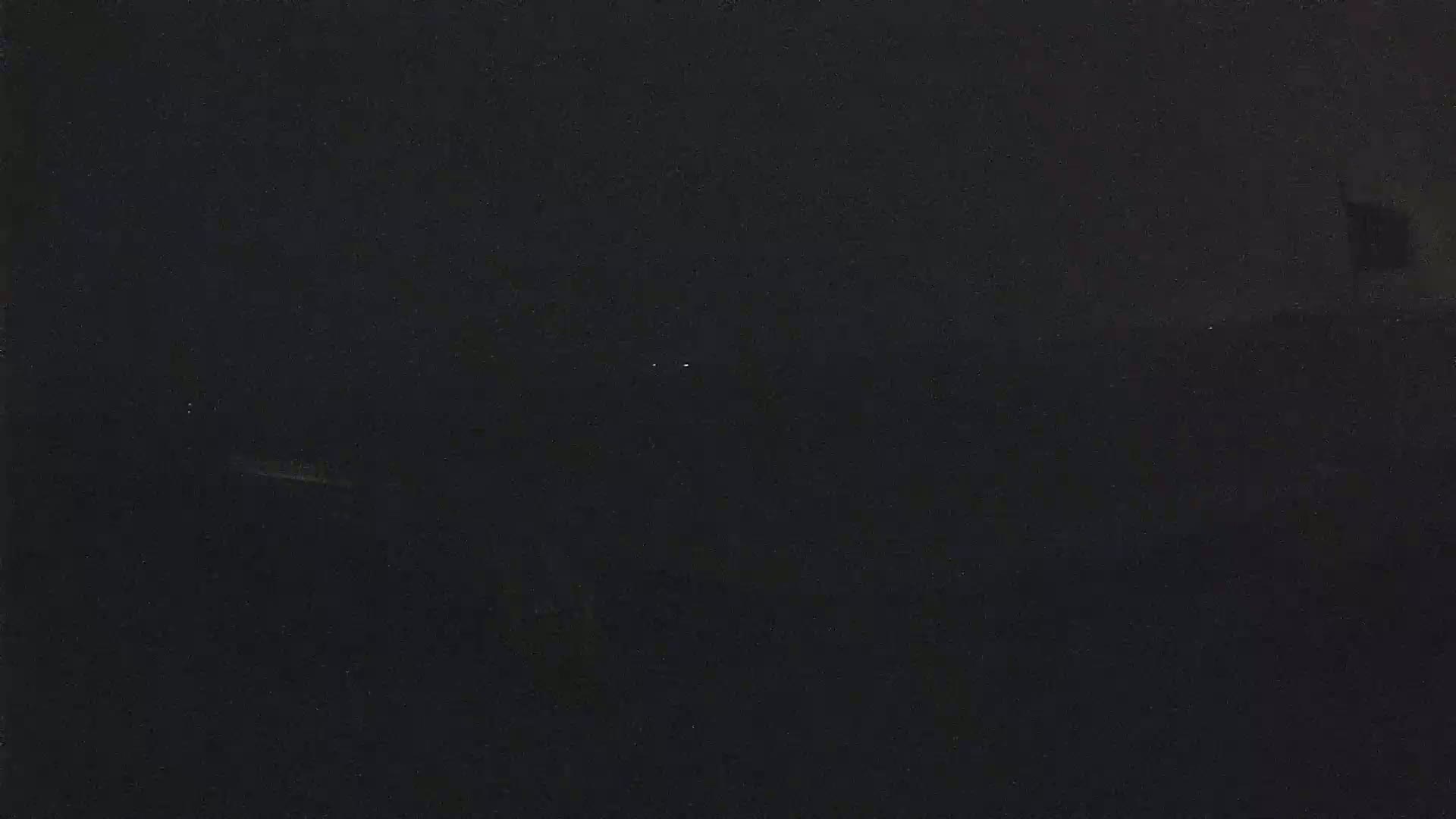 A dark, possibly nighttime, scene shows a few faint lights in the distance.