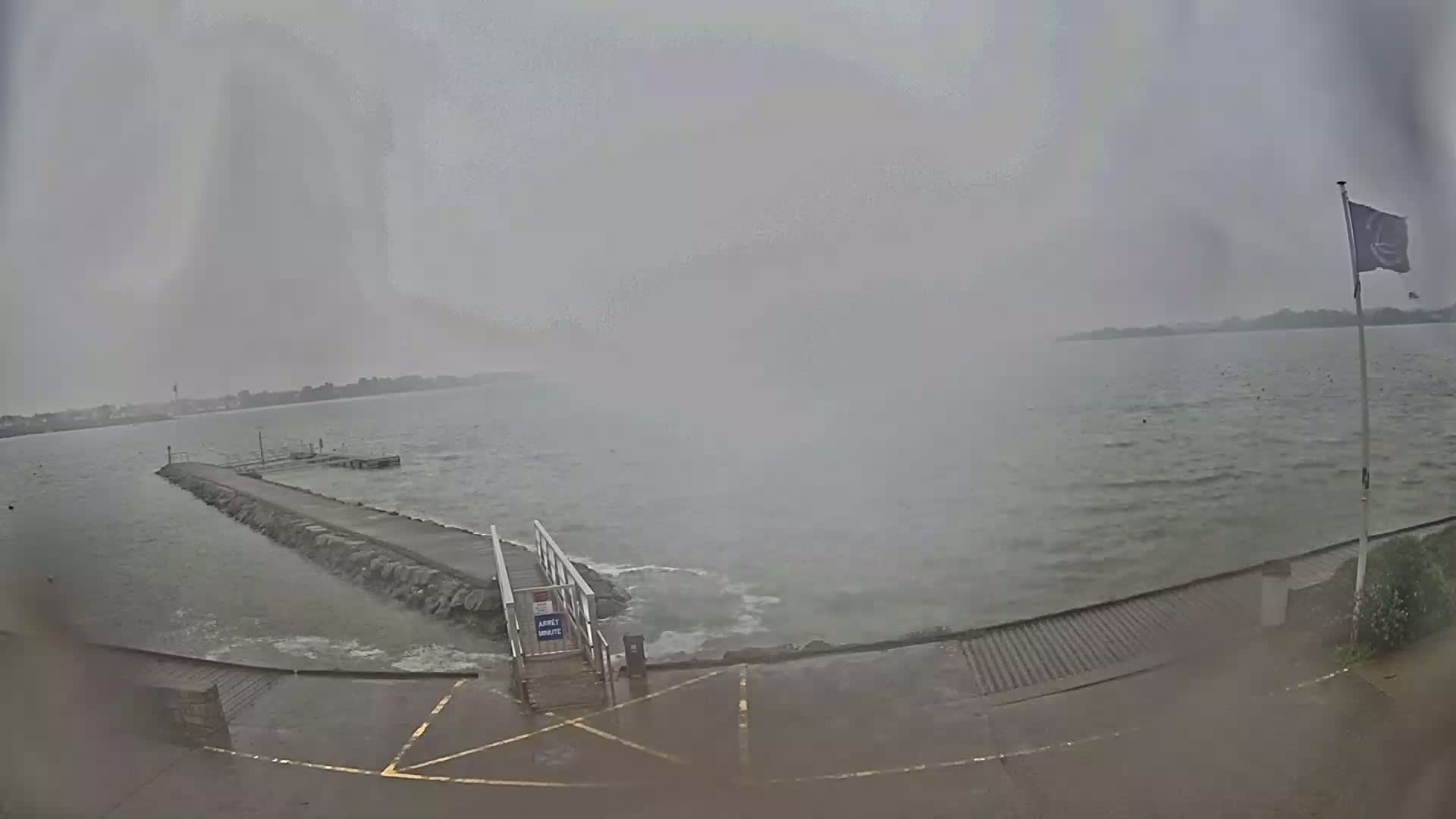 A rocky jetty extends into a choppy, grey sea under an overcast sky.