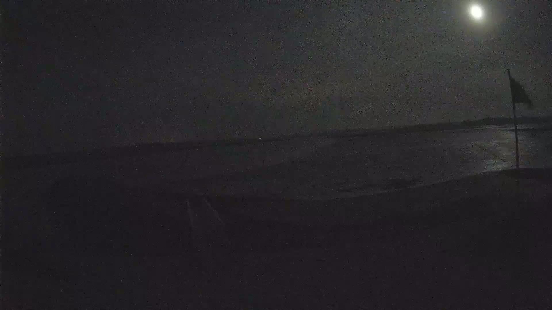 A nighttime scene shows a body of water under a bright moon.