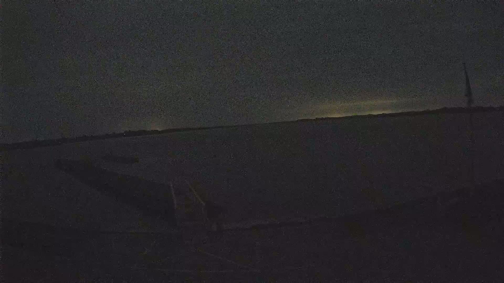A dark, nighttime scene shows a body of water under a mostly clear, dusky sky.