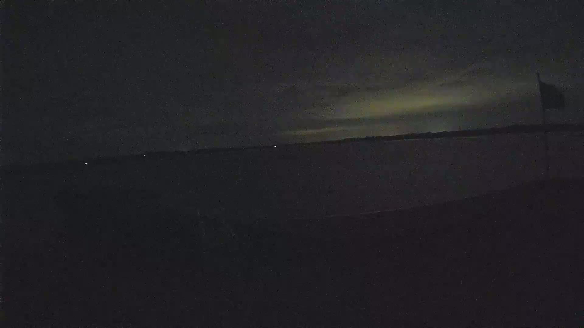 A dark body of water is visible under a night sky with a faint, light-colored horizon.