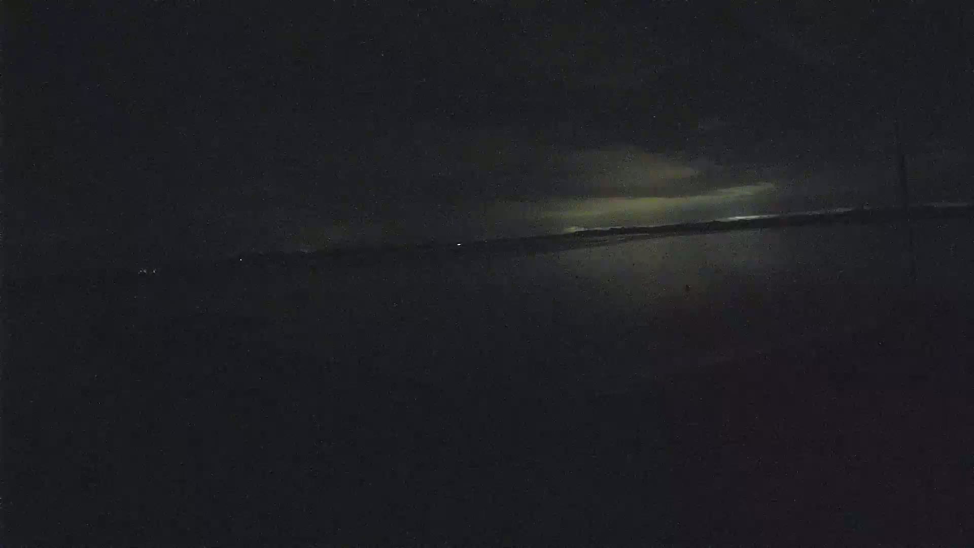A dark, nighttime scene shows a body of water reflecting a faintly illuminated sky.