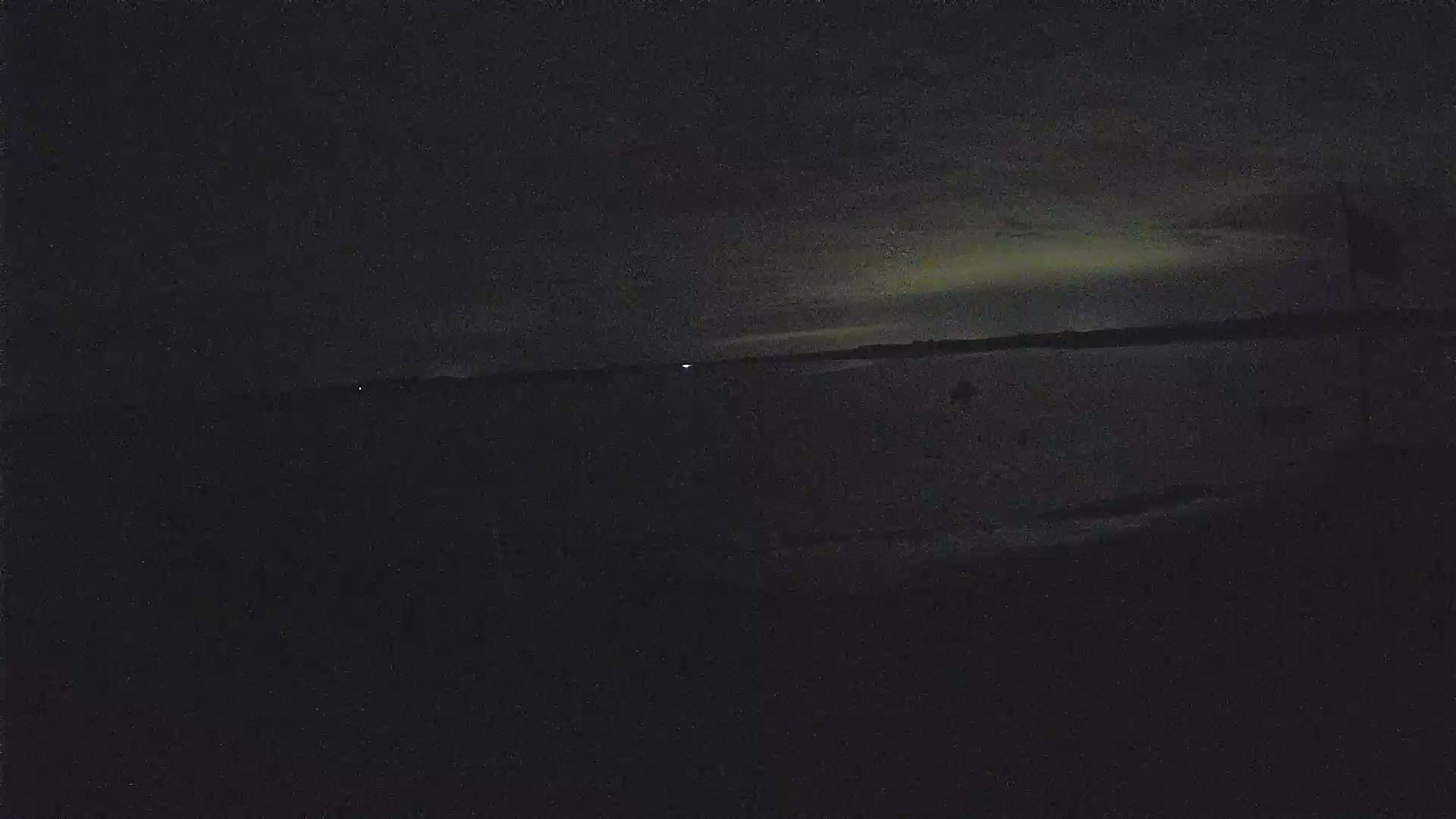 A dark, nighttime scene shows a body of water under a faintly illuminated sky.