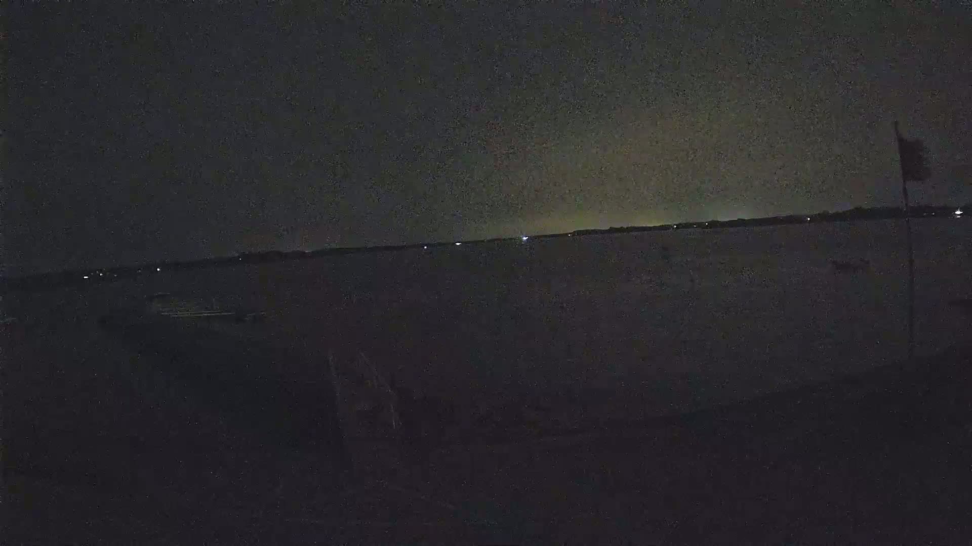 A dark, nighttime view of a body of water with a few distant lights visible on the opposite shore.