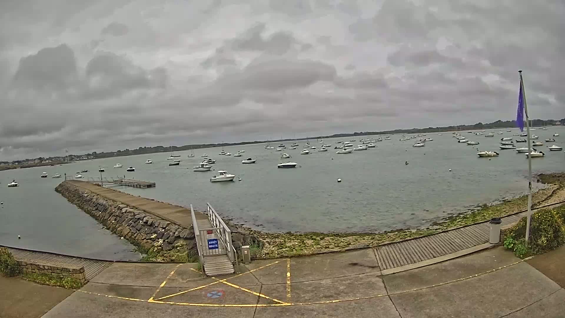 A calm body of water with numerous small boats anchored under an overcast sky.