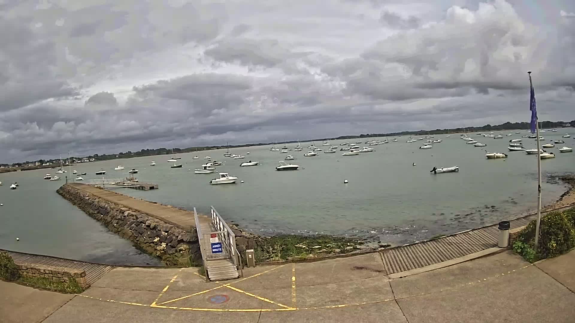 Numerous boats are moored in calm, shallow water under a cloudy sky.