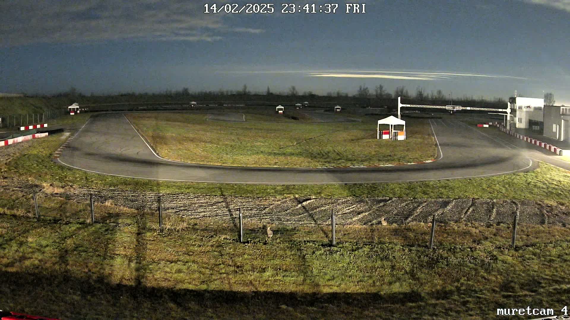 An empty go-kart track at night under a partly cloudy sky.