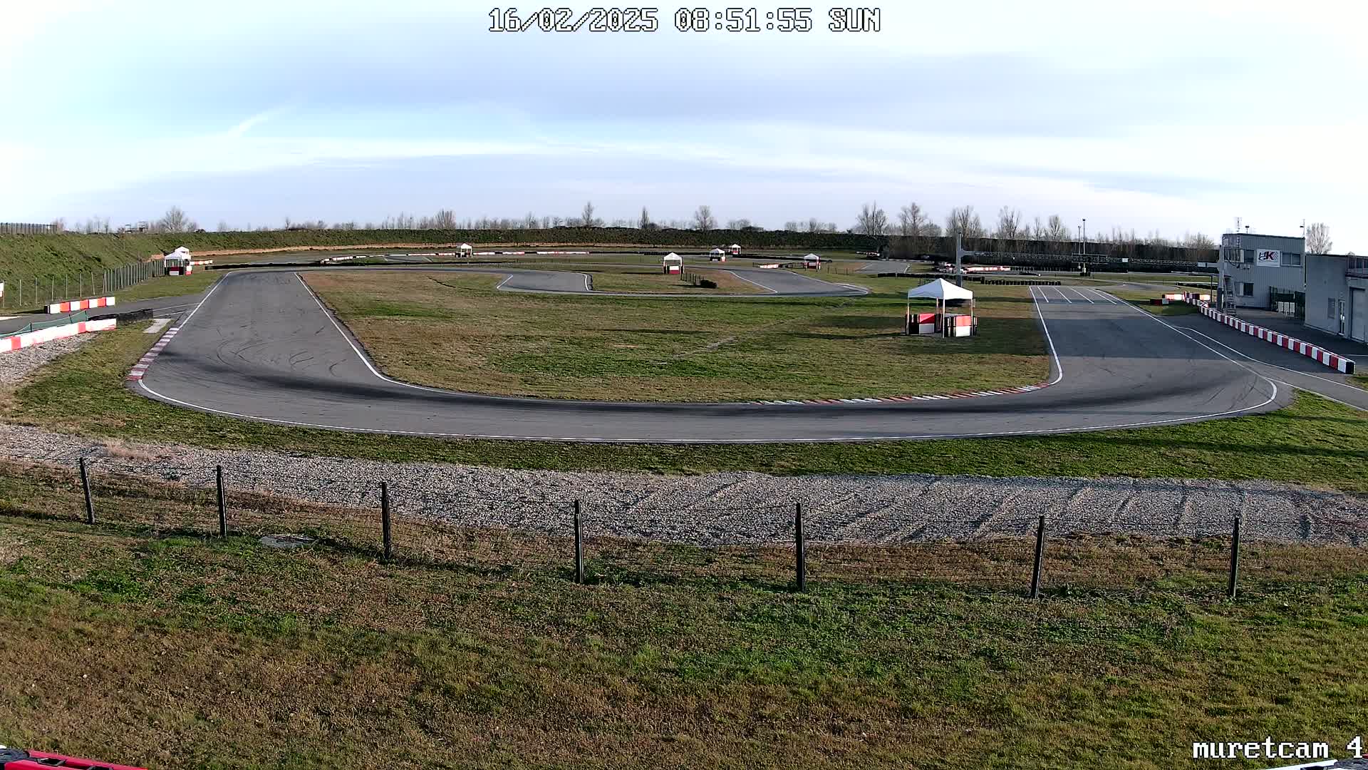 A go-kart track with a mostly sunny sky is seen from an elevated vantage point.
