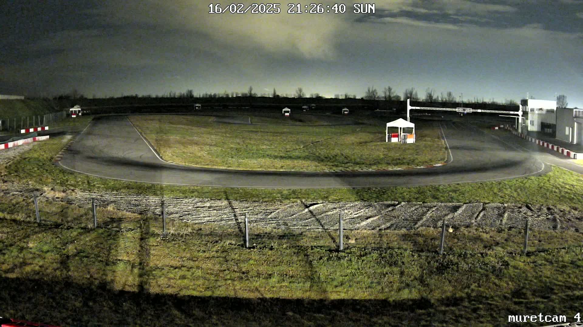 An empty go-kart track at night under a cloudy sky.