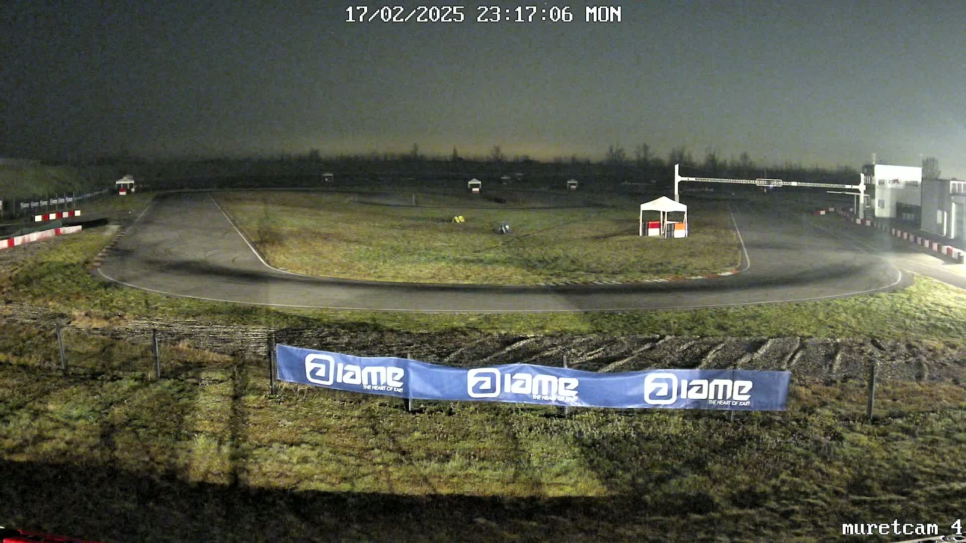 An empty go-kart track at night under a dark, overcast sky.