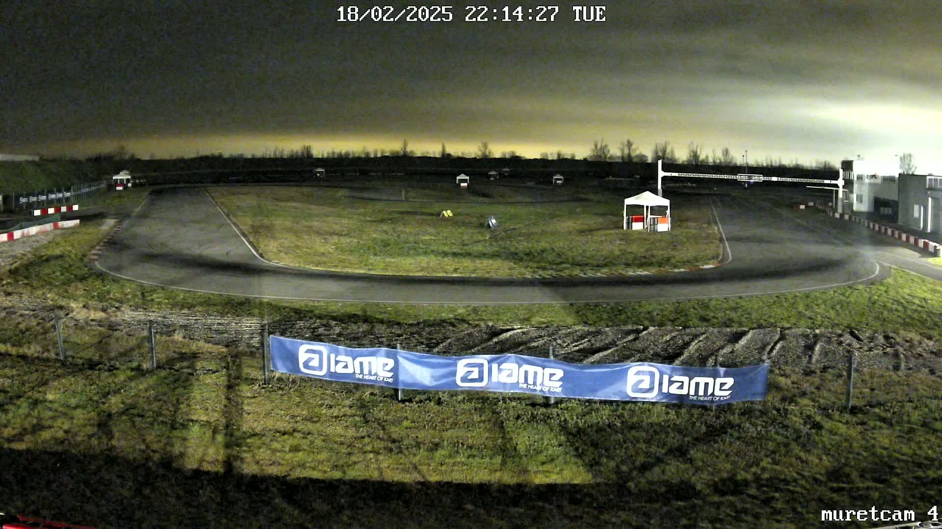 A nighttime view of an empty go-kart track under a dark, cloudy sky.