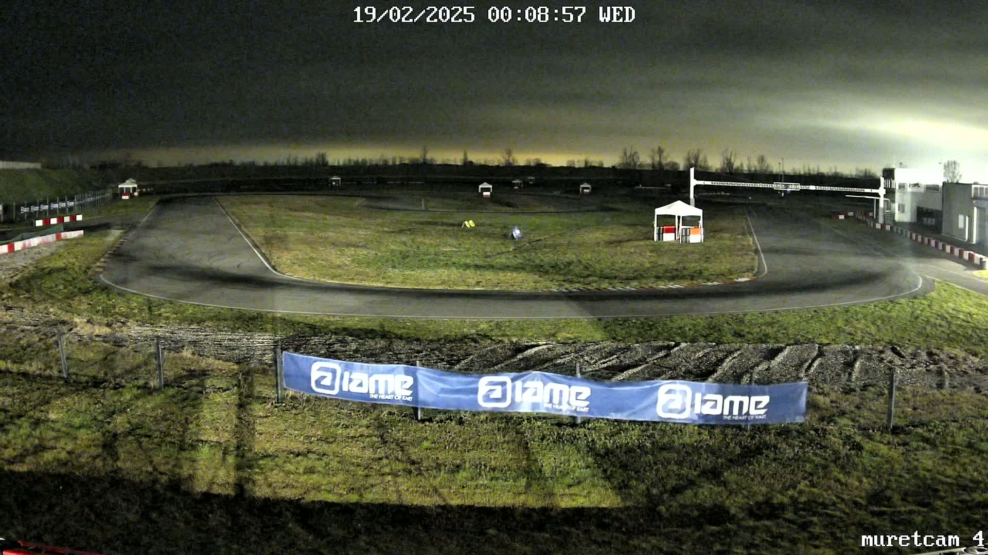 An empty go-kart track at night under a dark, cloudy sky.