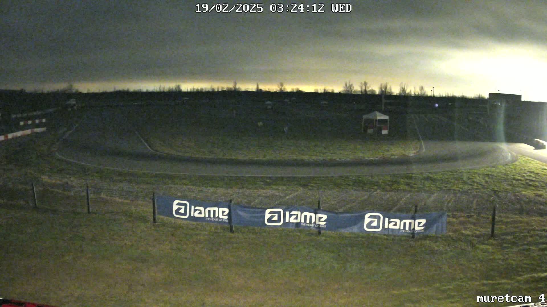 An empty go-kart track is visible under a dark, cloudy night sky.