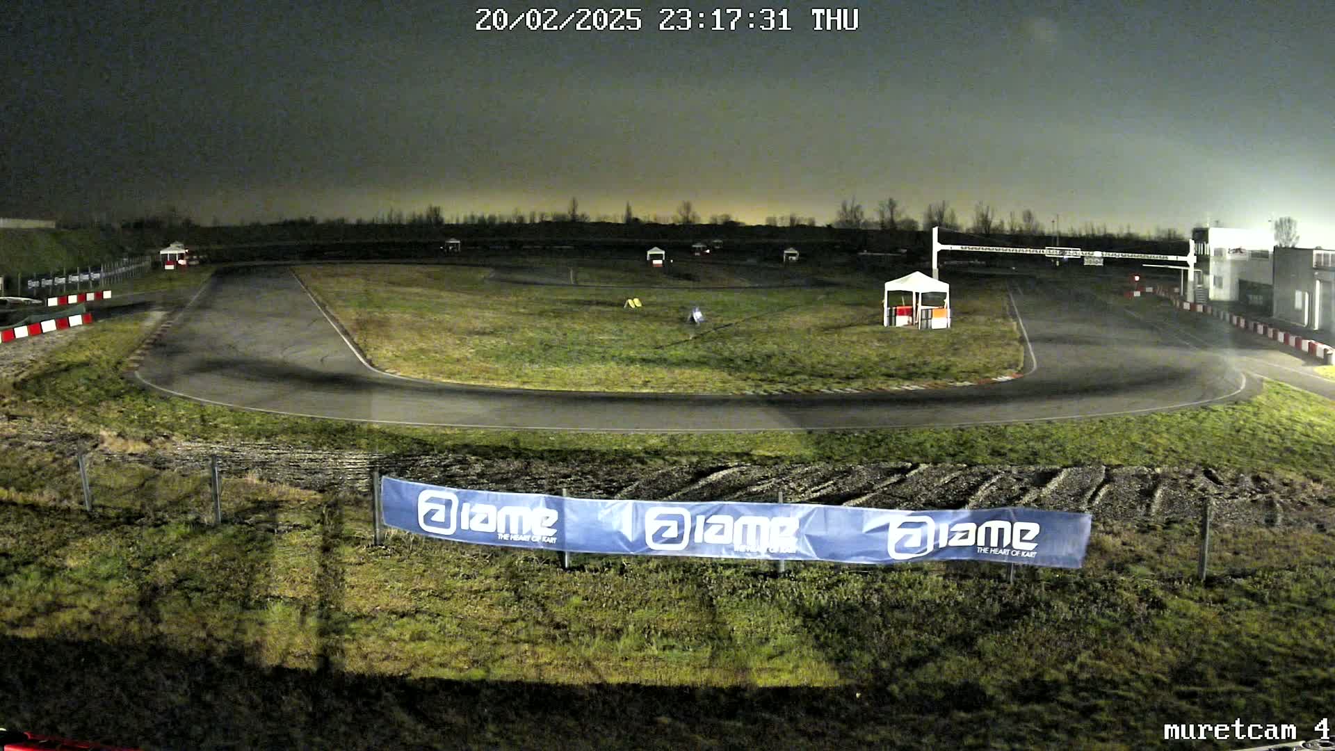 An empty go-kart track is visible at night under a dark, overcast sky.