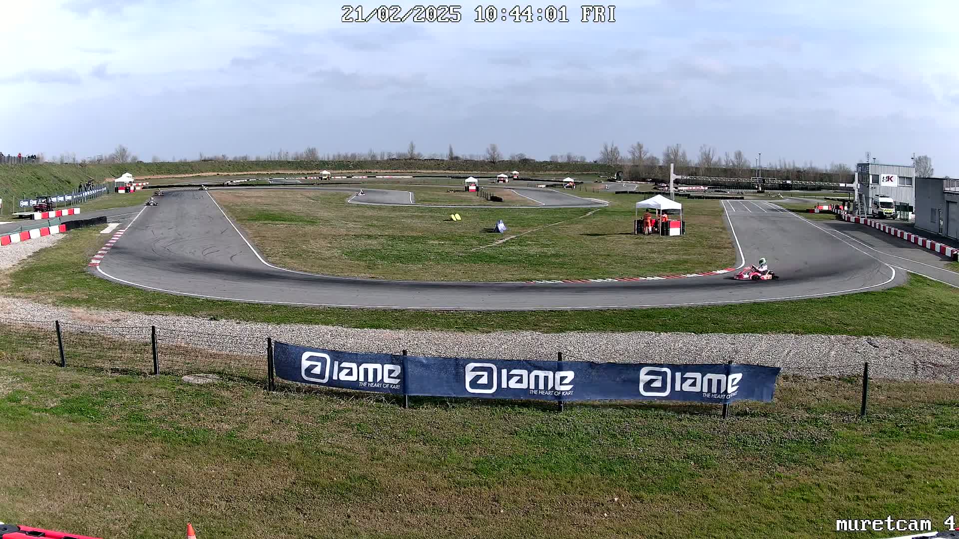 A go-kart race is underway on a sunny day at an outdoor track.
