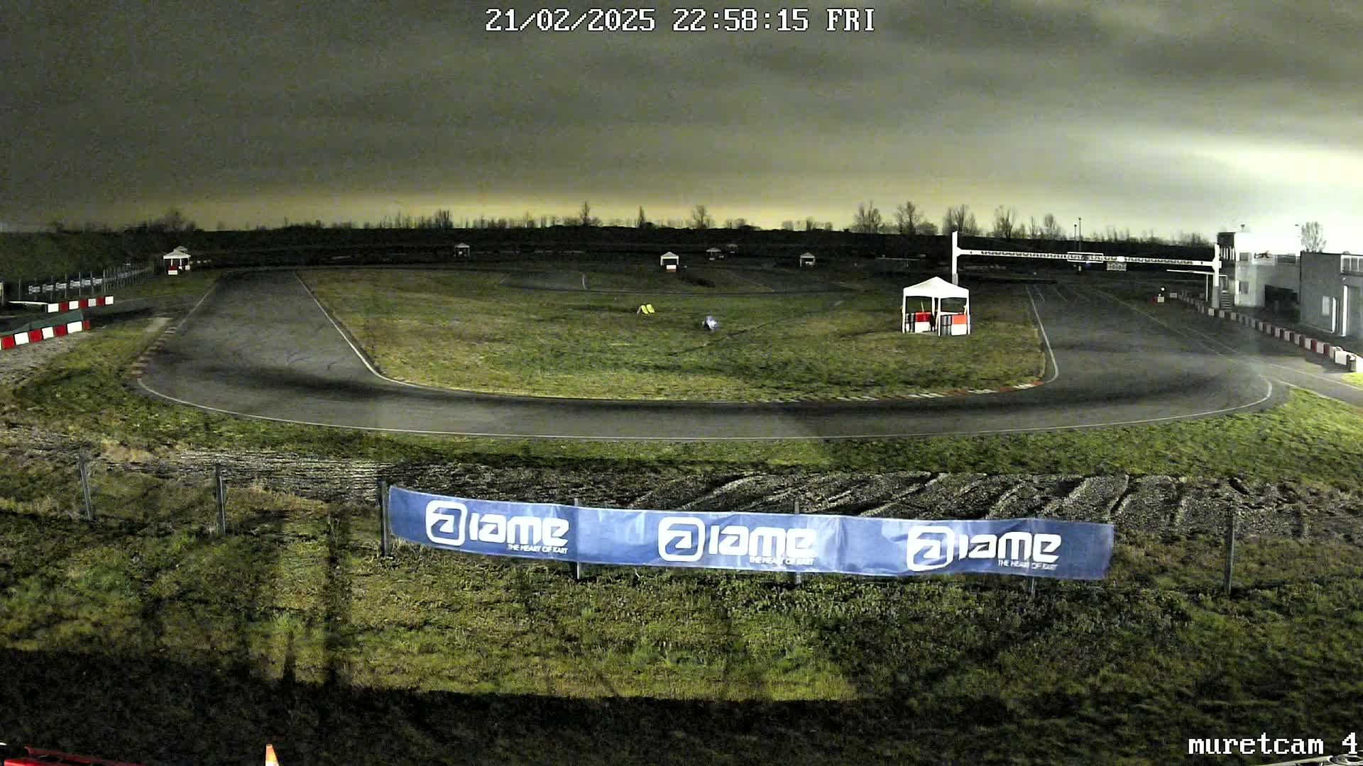 A nighttime view of an empty go-kart track under a dark, cloudy sky.