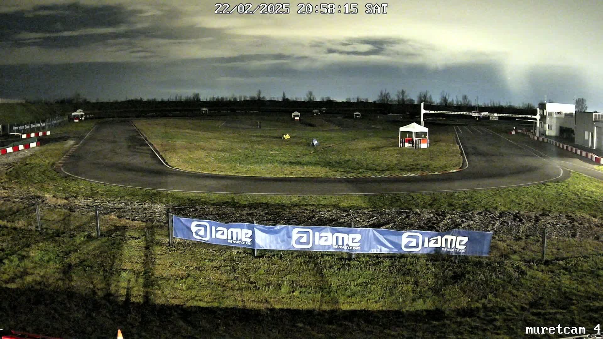 An empty go-kart track at night under a cloudy sky.