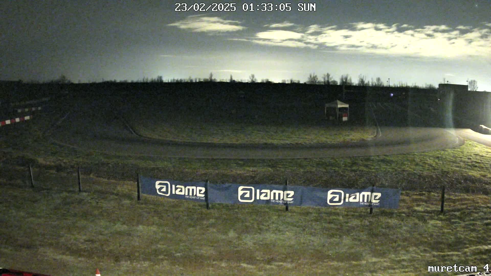 A nighttime view of a go-kart track under a partly cloudy sky.