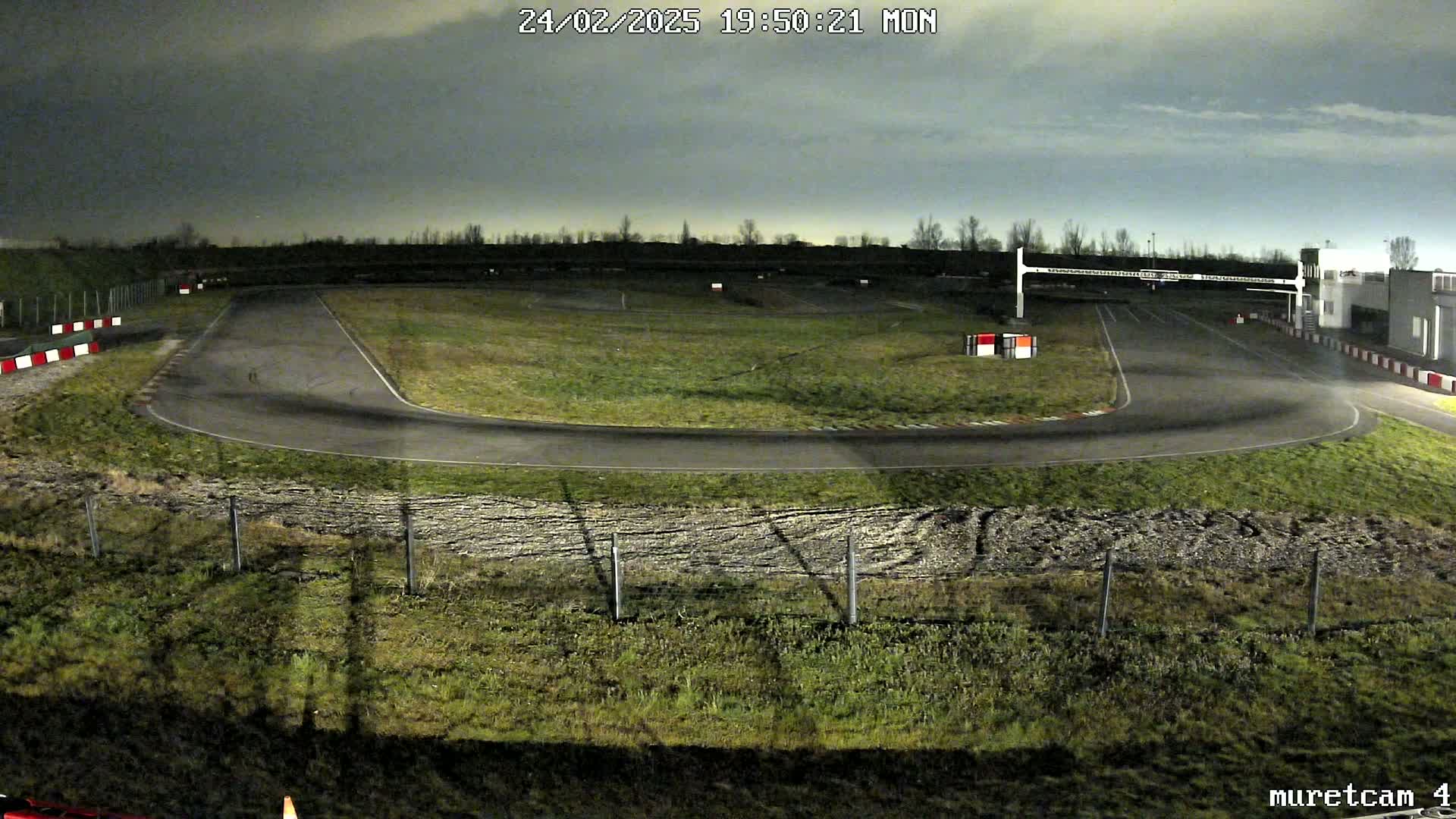An empty go-kart track at night under a cloudy sky.