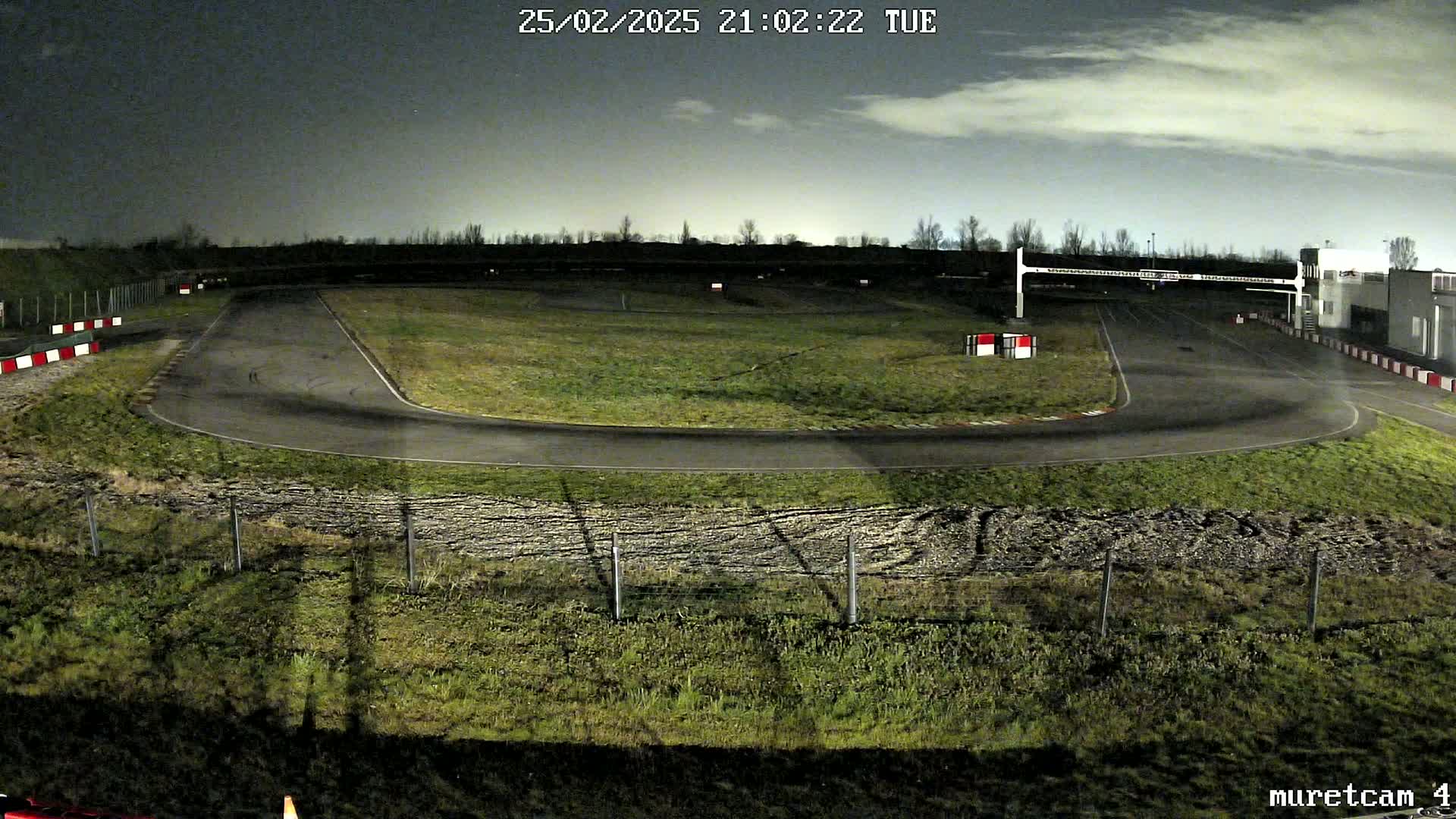 An empty go-kart track at night under a partly cloudy sky.