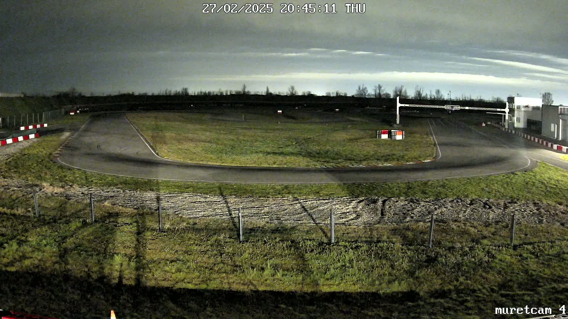 A nighttime view of a go-kart track under a cloudy sky.
