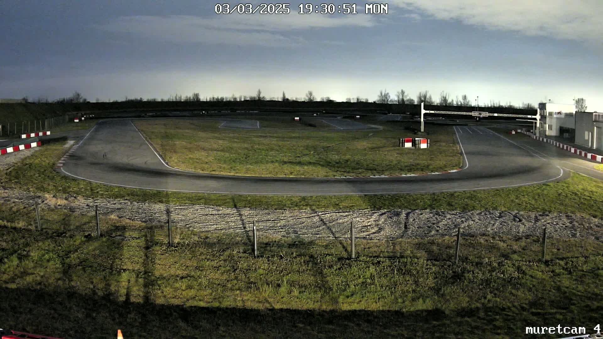 An empty go-kart track under a cloudy twilight sky.