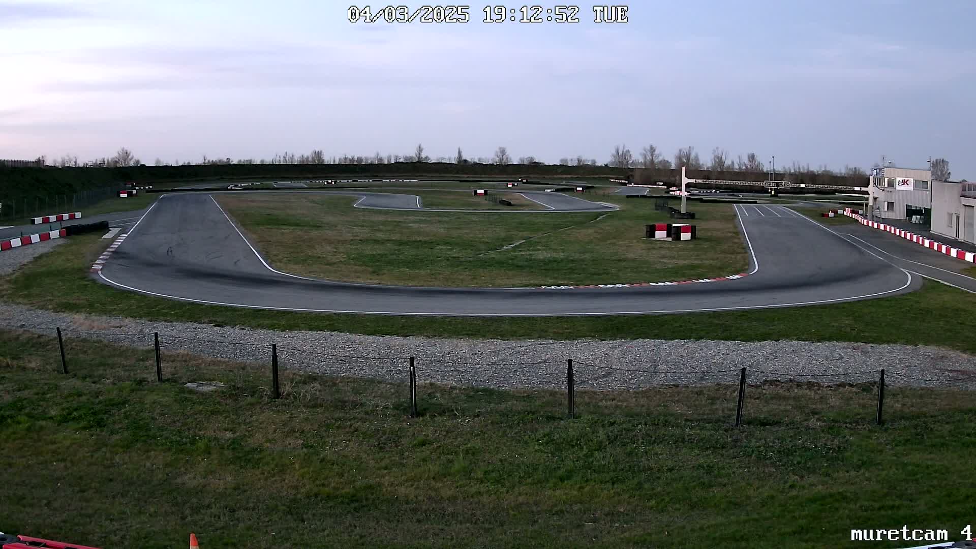 An empty go-kart track under a cloudy sky at dusk.