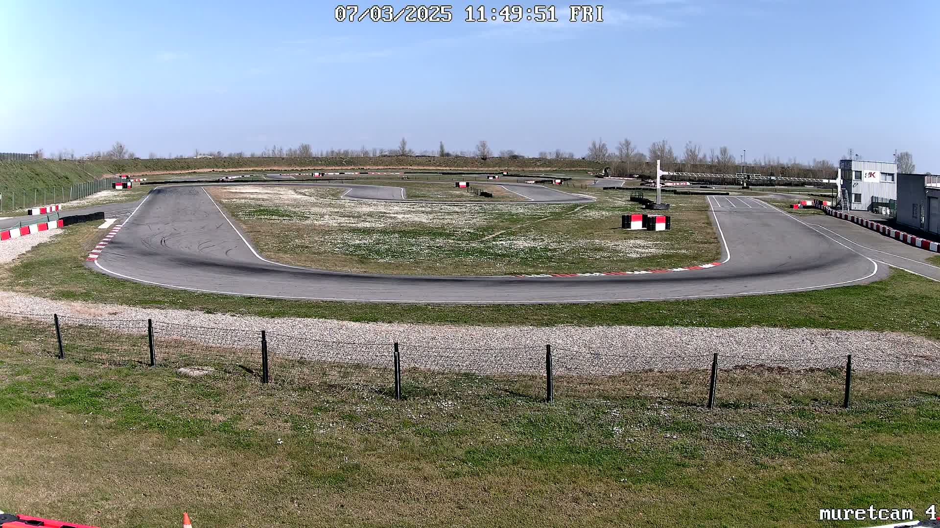 An outdoor go-kart track on a sunny day with grassy areas surrounding the asphalt course.