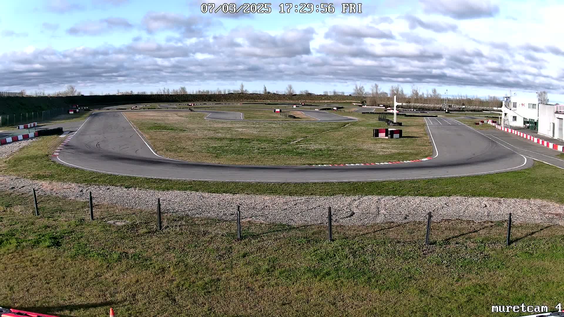 An outdoor go-kart track on a partly cloudy day.
