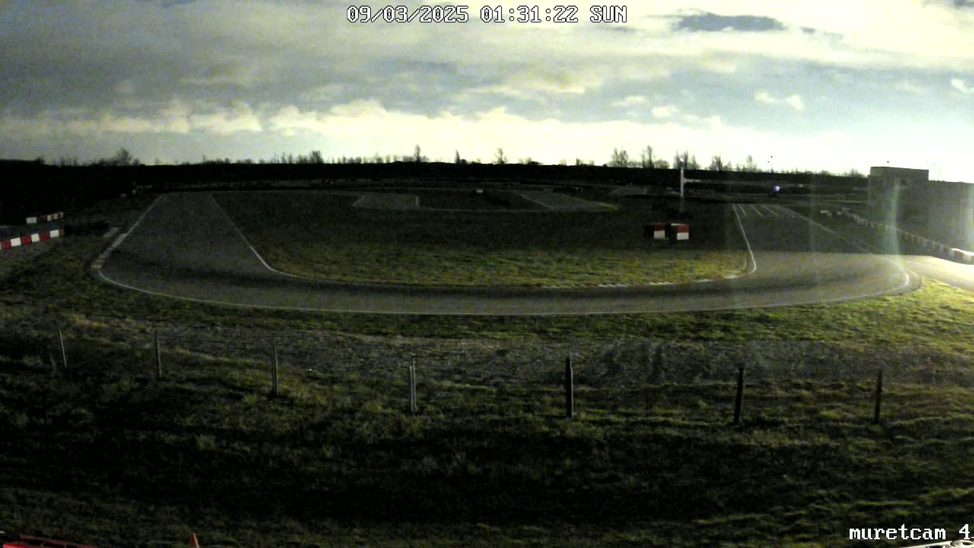 An empty go-kart track is visible under a dark, cloudy night sky.