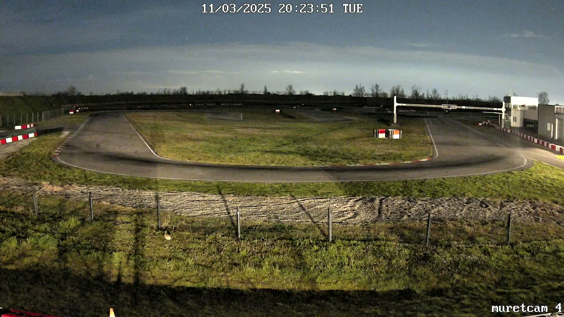 An empty go-kart track at night under a mostly clear sky.