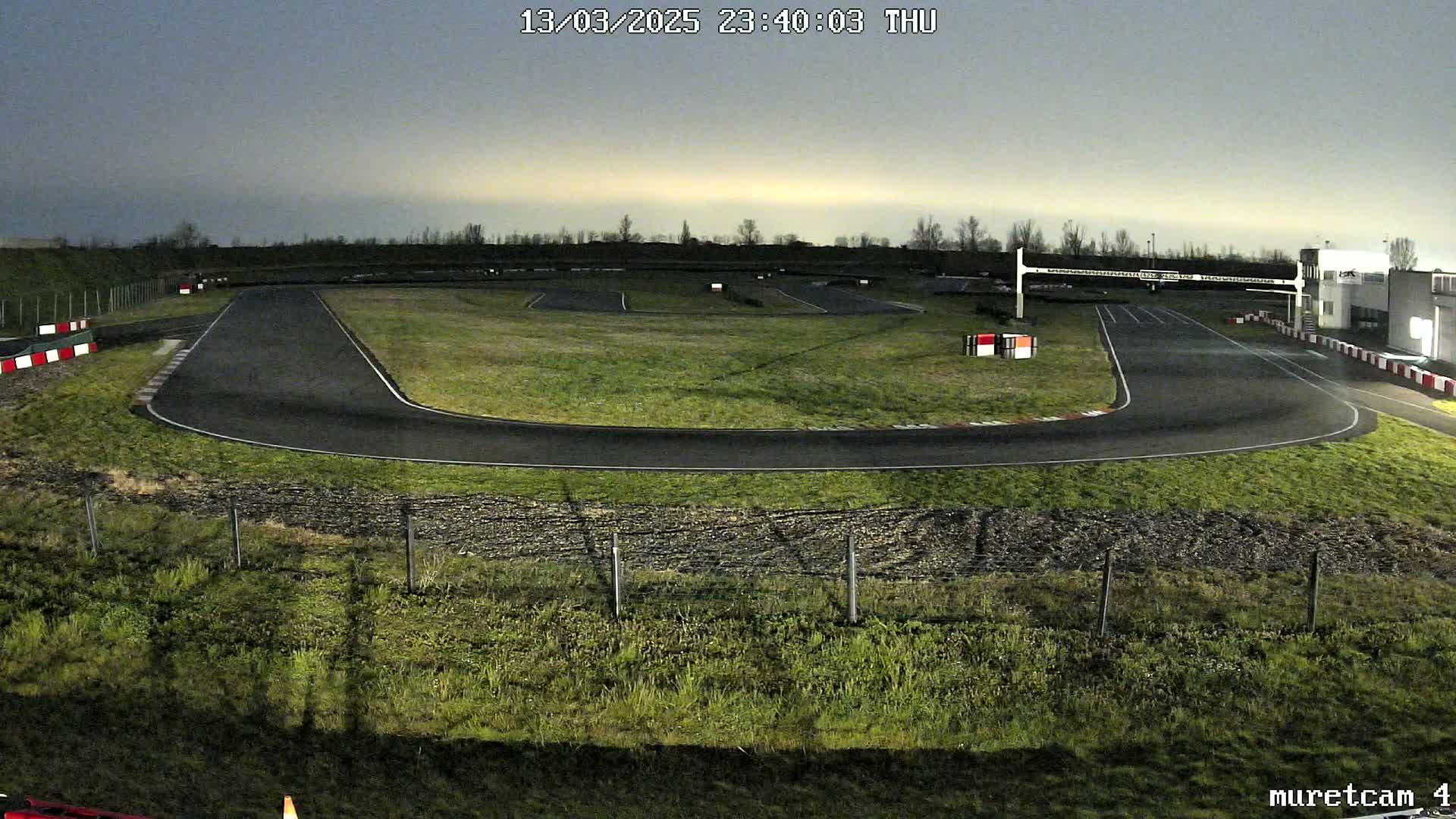 An empty go-kart track at night under a twilight sky.