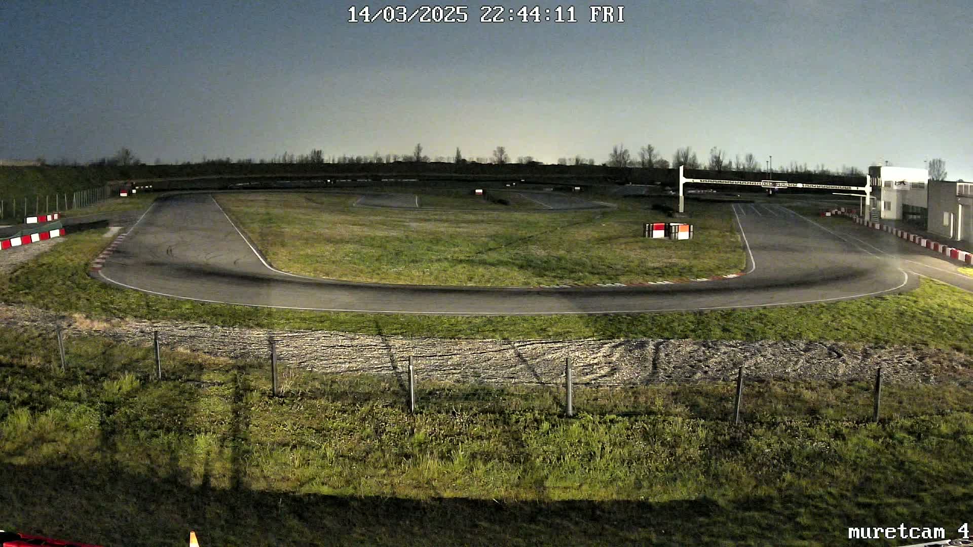 An empty go-kart track at night under a dusky sky.