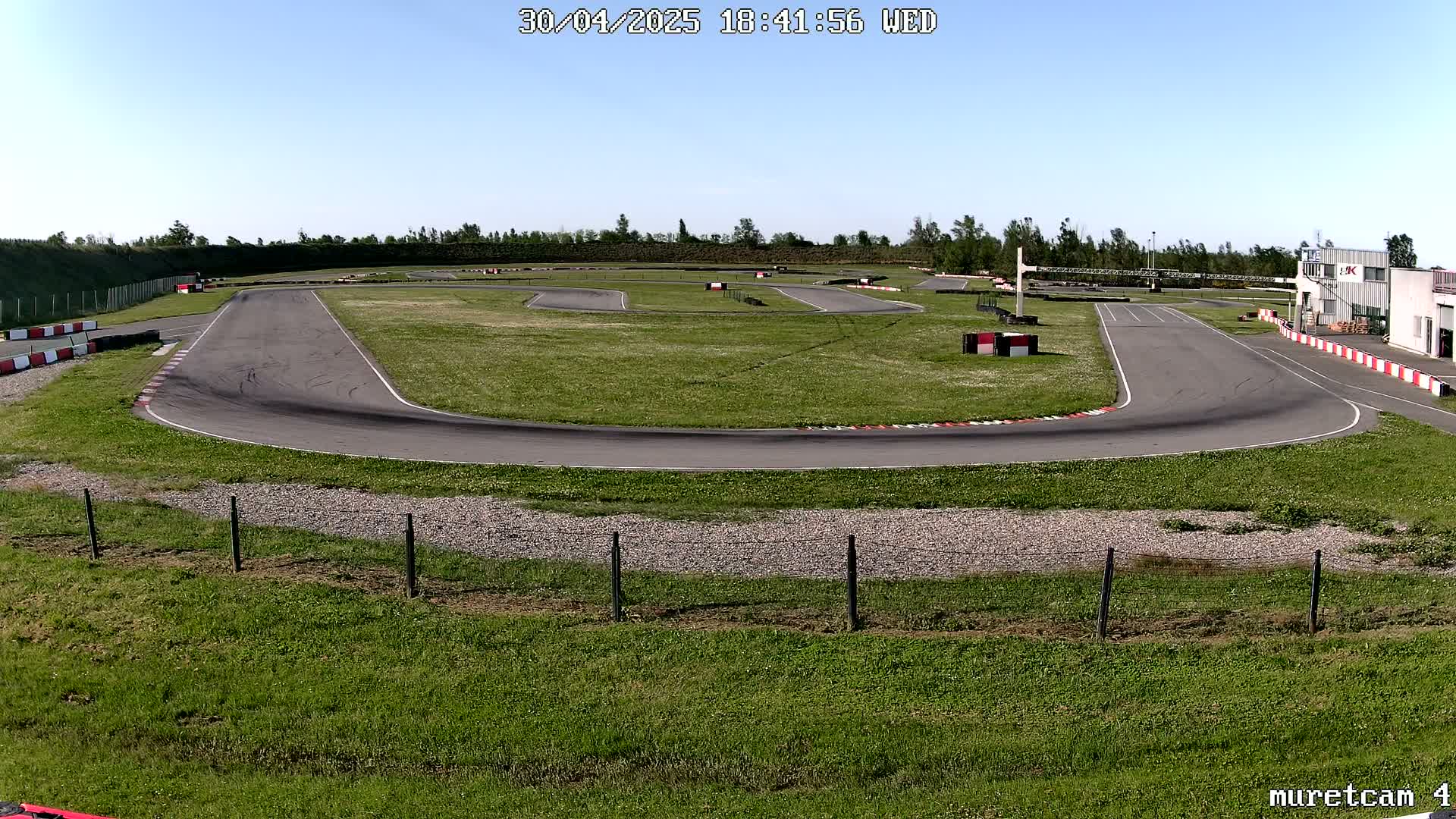 An outdoor go-kart track on a sunny day with green grass surrounding the asphalt course.