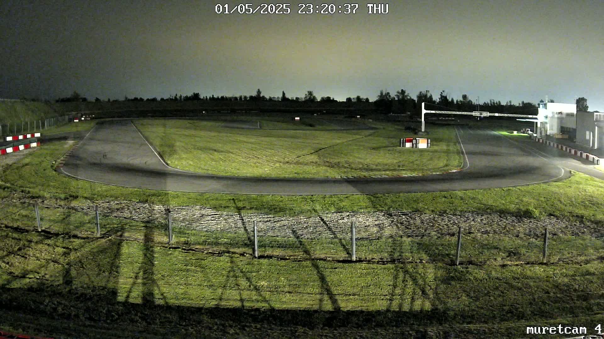 An empty go-kart track at night under a cloudy sky.