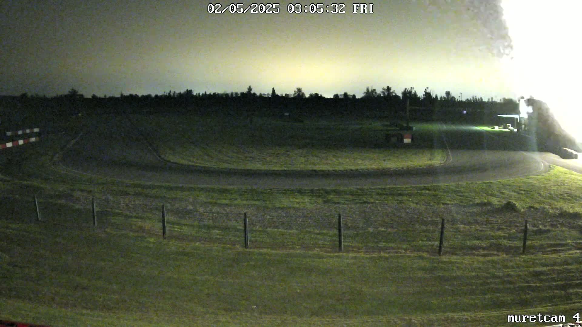 A nighttime view of a go-kart track under a pale, overcast sky.