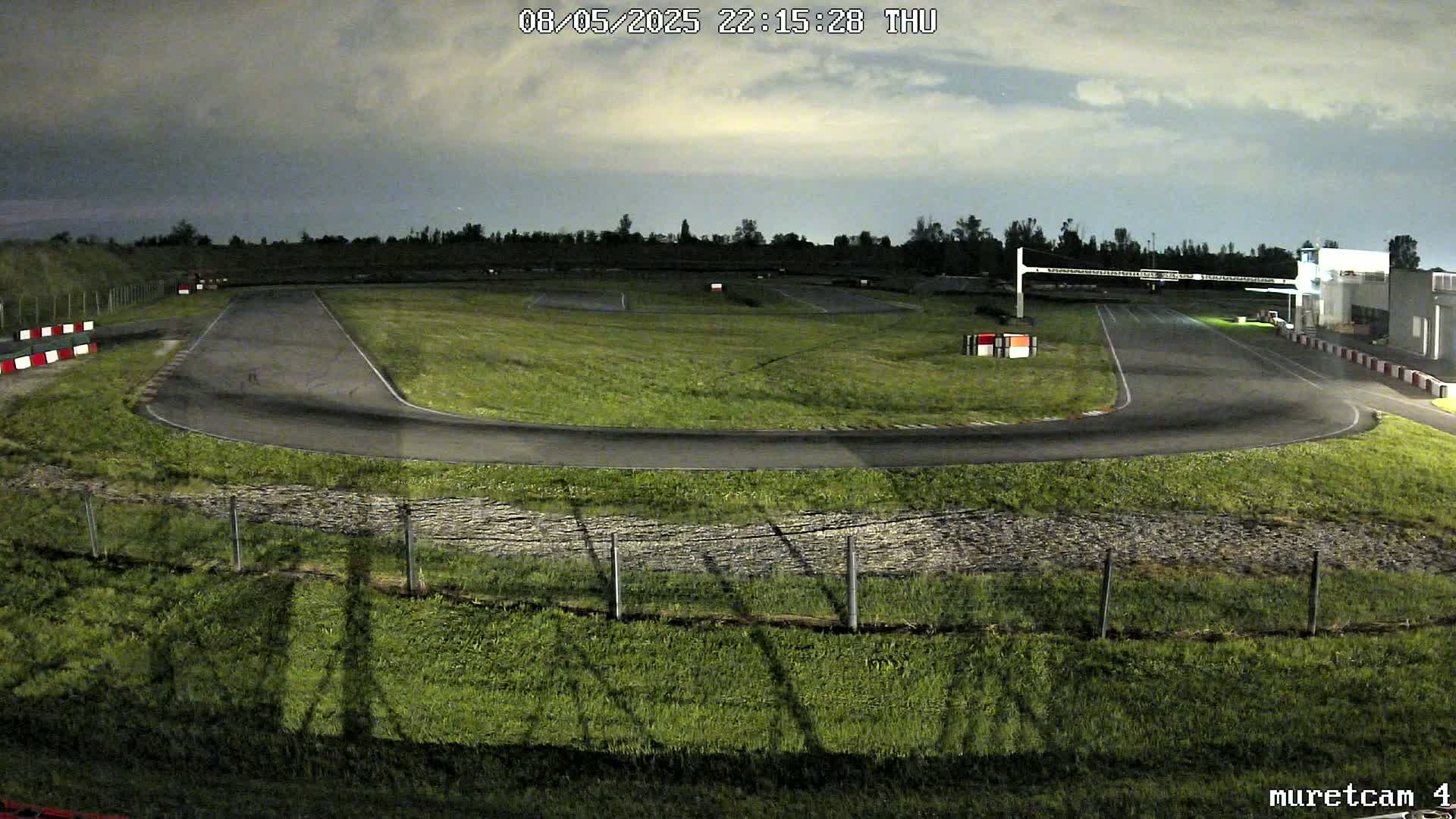 An empty go-kart track at night under a cloudy sky.