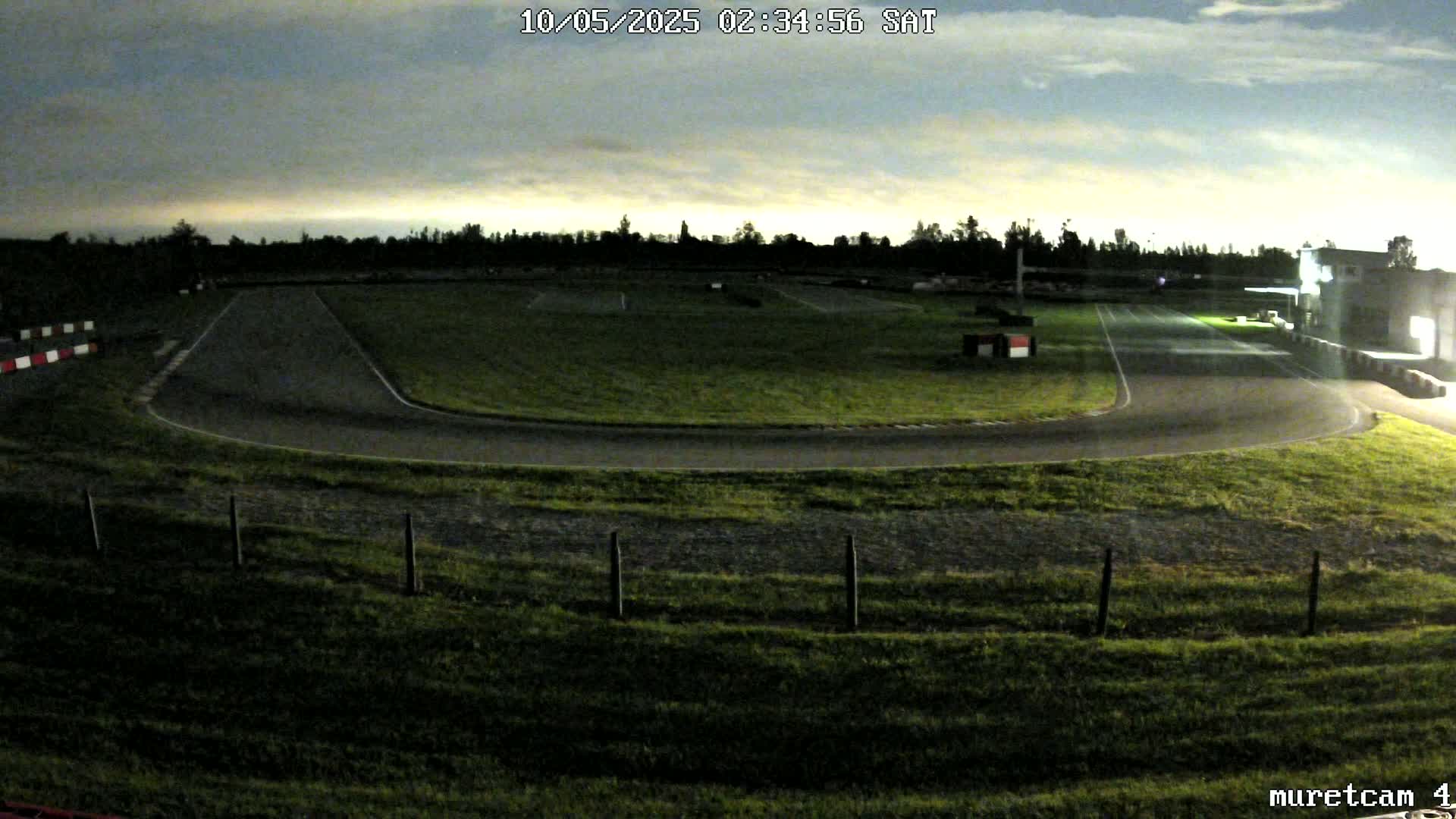 A dimly lit go-kart track under a cloudy night sky.