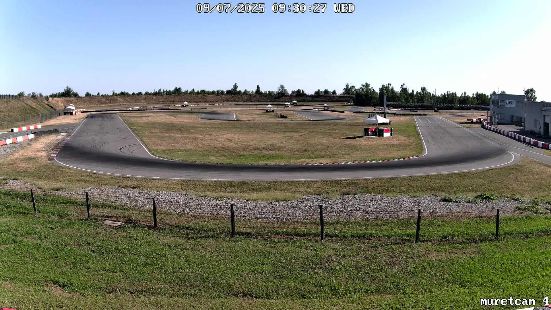 A go-kart track on a sunny day with dry, brown grass surrounding the asphalt.