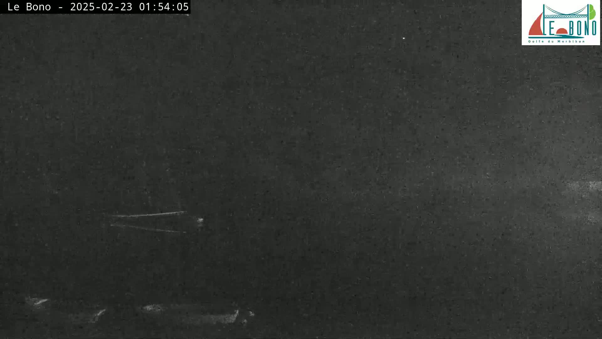 A dark, nighttime scene shows a mostly featureless expanse with a faint light source in the distance.
