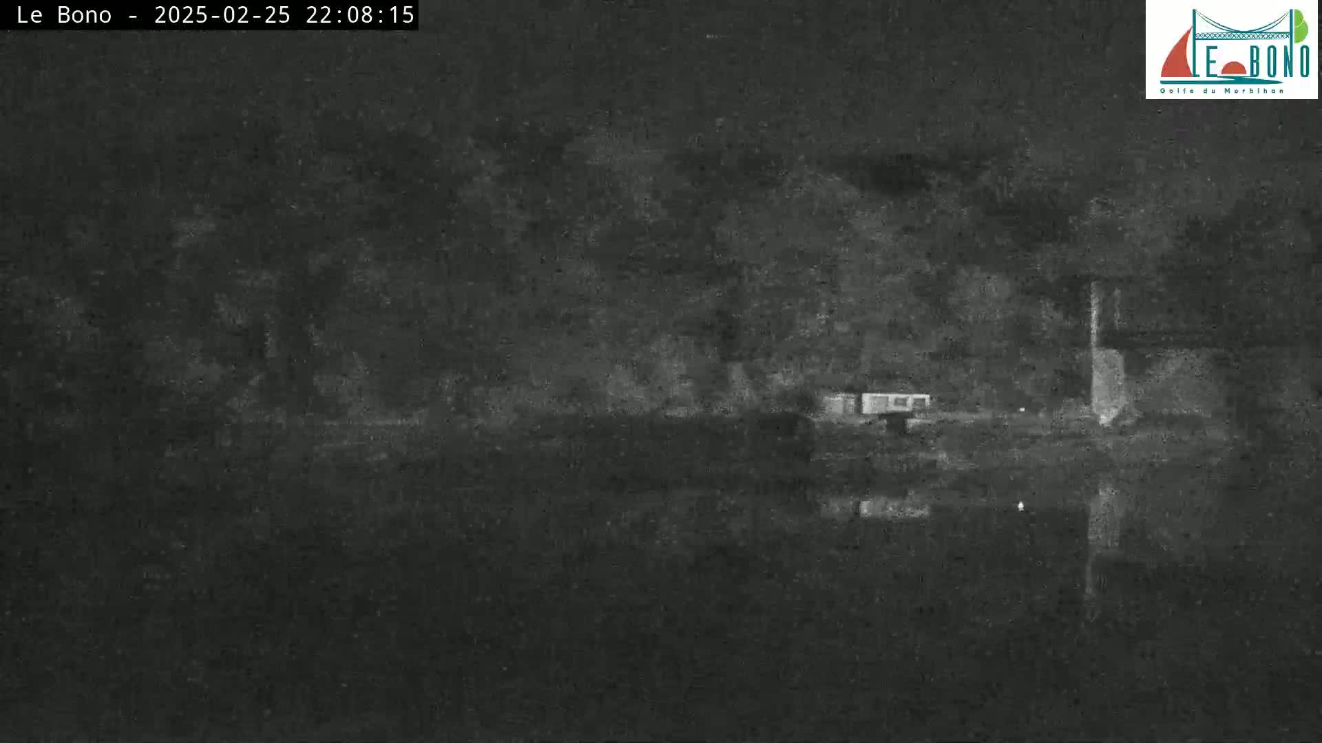 A nighttime, low-light image shows dark trees and water reflecting a dark sky.