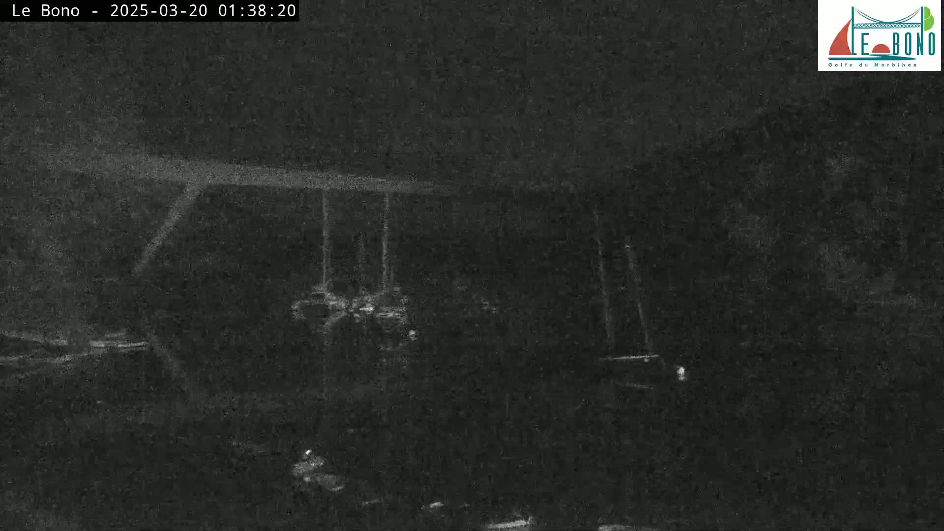 A low-light nighttime image shows a dark, possibly outdoor scene with indistinct objects and a structure that resembles a bridge or overpass.