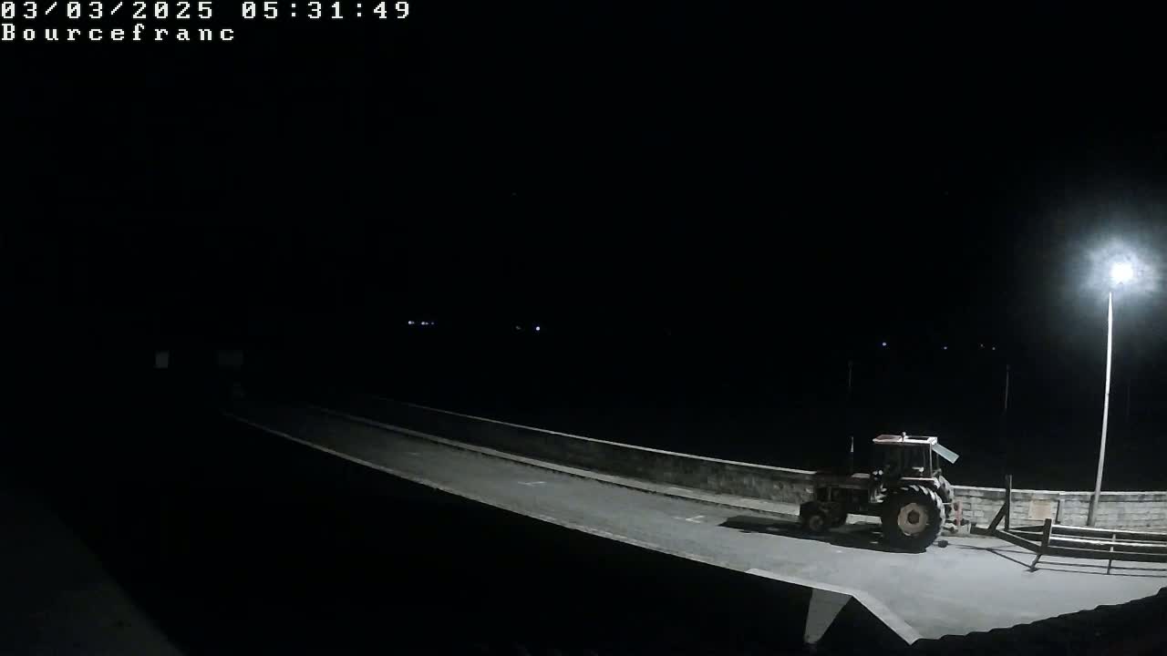 A tractor is parked on a dark road at night, illuminated by a streetlight.