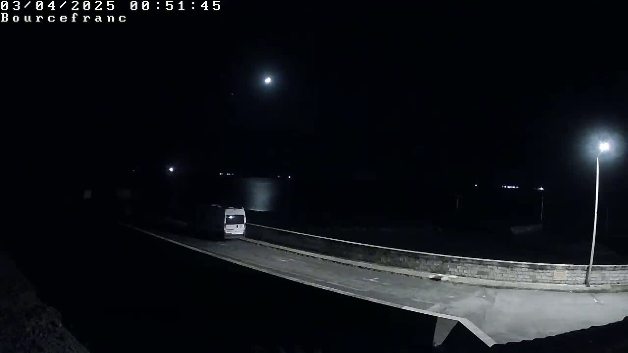 A white van drives on a dark road at night under a bright moon.