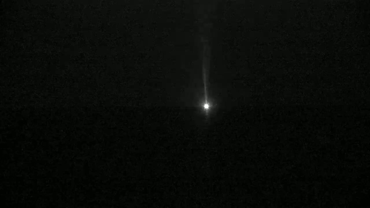 A bright light streaks across a dark night sky.