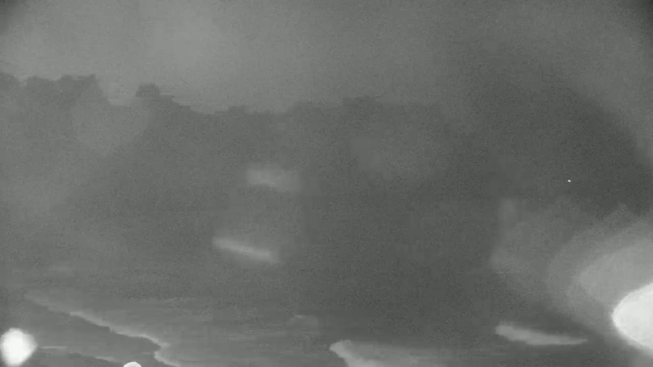 A blurry, low-light image shows a dark, possibly overcast sky over a dark landscape with faint, indistinct features at the horizon.