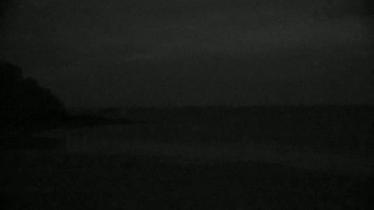 A dark, blurry image shows a dark body of water under a dark, possibly nighttime sky.