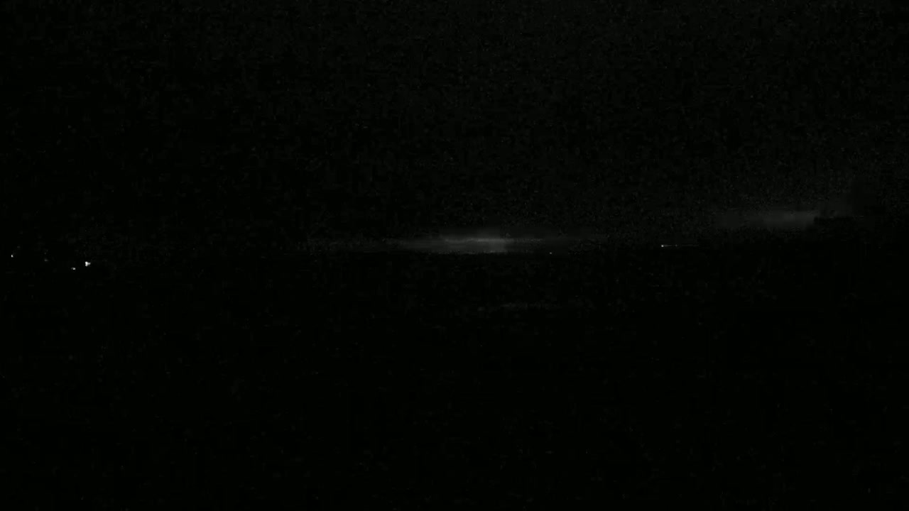 A dark, nighttime landscape is shown with a faint, horizontally-oriented glow on the horizon.
