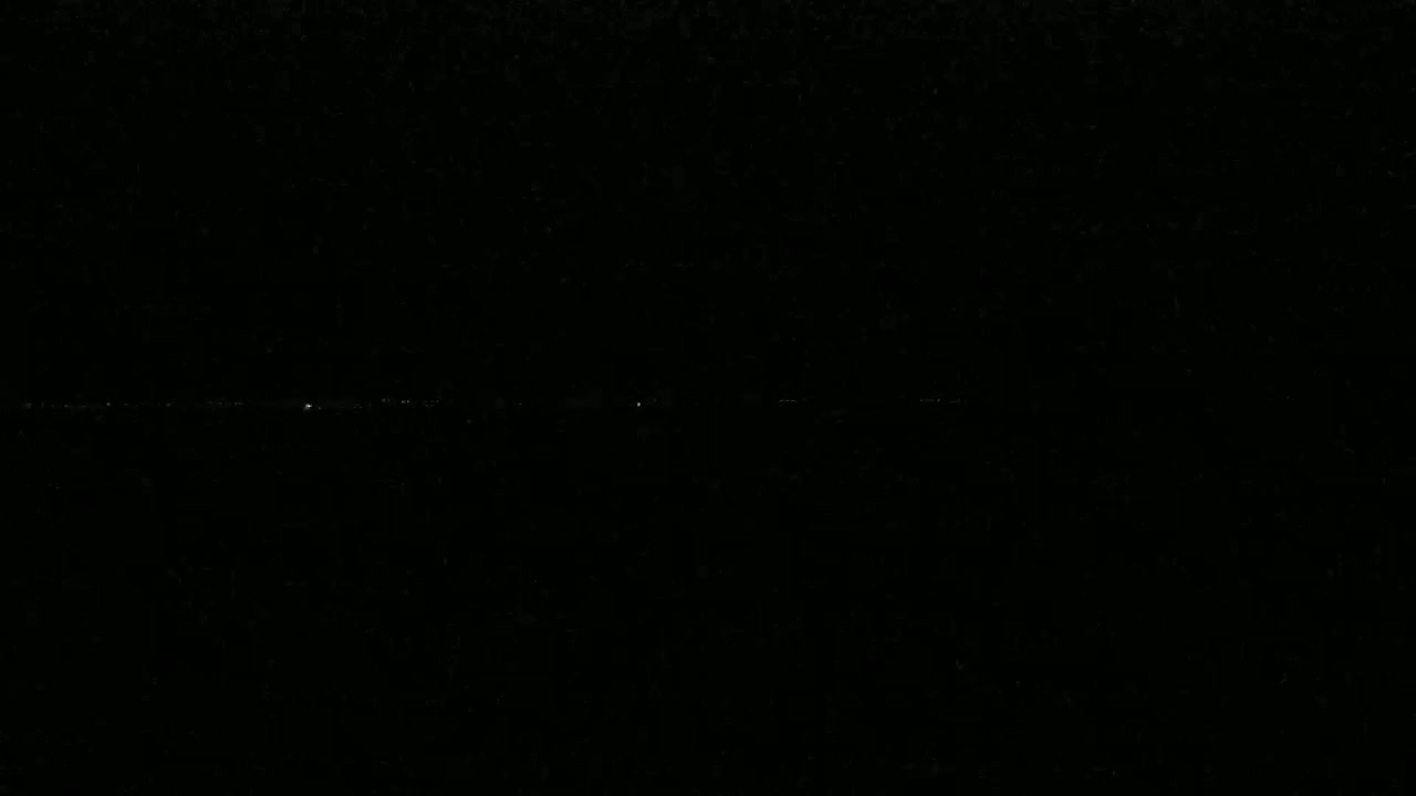 A dimly lit horizon line shows a few faint lights in the distance at night.
